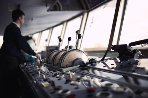 Imagen detallada de una cabina de barco donde se observa claramente una palanca de motor para barco con tres controles diferentes utilizada en maniobras de navegación