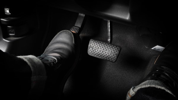Conductor o pasajero del asiento izquierdo usando un pedal oscuro, cuya función se activa por un chicote de clutch o freno.